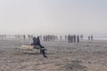 Crowd of people walking on a beach on foggy spring day