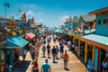 A crowd of people walking down a bustling wooden walkway lined with colorful shops, A bustling boardwalk lined with colorful shops