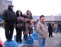 A crowd of people in the winter standing on a bench waiting for the event watching