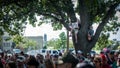 Crowd protesting vaccine mandates with child in tree holding sign