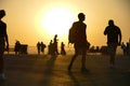 Crowd silhouettes on seaside promenade at sunset