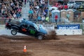 Crowd watches as a massive truck performs stunts in the dirt at an event Royalty Free Stock Photo