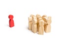 The crowd of wooden figures of people stand distantly and look at the red man. The rejected person tries to establish contact with Royalty Free Stock Photo