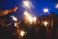 A crowd of young happy people with bengal fire sparklers in their hands during birthday celebration