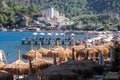 Crowded beach in touristic resort village in Turkey. Straw umbrellas hats on the beach at sunny day. Seaside embankment