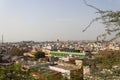 A crowded city shot from a high angle view point with Acacia tree branches in front and blue sky in background. Royalty Free Stock Photo