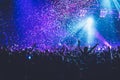 A crowded concert hall with scene stage lights, rock show performance, with people silhouette, colourful confetti explosion fired