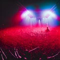 A crowded concert hall with scene stage in red lights, rock show performance, with people silhouette, dance floor during a concer