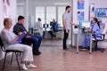 Crowded hospital waiting area with people filling form for medical consultation Royalty Free Stock Photo