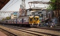 A crowded local EMU train of Indian railway approaches the station. people leaning.