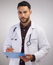 A crowded space and no mask Tsk Tsk. a handsome young doctor standing alone in the studio and writing on a clipboard.