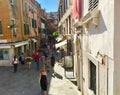 A crowded street full of tourists exploring the stores and restaurants surrounded by beautiful old Venetian architecture