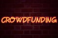 Crowdfunding neon sign on brick wall background. Fluorescent Neon tube Sign on brickwork Business concept for Business Fundraising