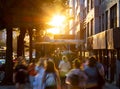 Crowds of diverse people walking down the sidewalks of 14th Street with the bright light of summer sunset shining above in New