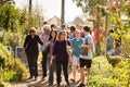 Crowds of diverse people walking through plant nursery garden at outdoor farmer`s market