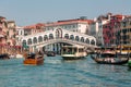 Crowds of tourists and boats at the famous Rialto Bridge spanning the Grand Canal of the city of Venice