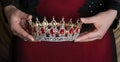 Crown with red gemstones in hands. Succesful