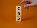 CRP - C-Reactive Protein Test symbol. Wooden cubes with word CRP. Doctor hand. Beautiful orange background. Medical and C-Reactive