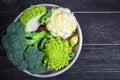 Cruciferous vegetables. Romanesco, cauliflower and broccoli on a round tray on a wooden background. Flat lay. Top view