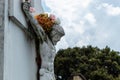 Crucified White JesusChrist Stone into a Cemetery adorned with multicolor flowers