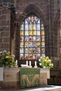 Crucifix, altar, and stained glass window inside of a church