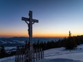 Crucifix from the back on a snowy mountain during sunset