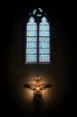 Crucifix in church under stained glass window.
