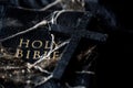 Crucifix on dirty Holy Bible in dark vintage