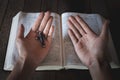 A crucifix in the hand of a young woman praying with the palm Put on the Bible The sacred blessings of God in the church, the