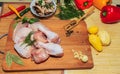 Crude chicken meat on a kitchen table, vegetables and kitchen accessories lie nearby