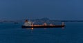 Crude oil tanker with navigation lights anchored in front of an oil storage terminal at night