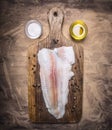 Crude Pangasius on a cutting board with butter and salt wooden rustic background top view close up