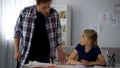 Cruel father shouting at daughter for wrong done homework, threatening to punish