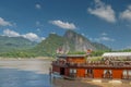 A cruise boat cruising along the banks of the Mekong River at Pak Ou Caves near Luang Prabang, Laos Royalty Free Stock Photo