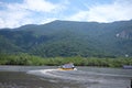 A cruise boat touring the small river close to Bertioga Brazil on a sunny day before the hills with green woods, wild