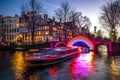 Cruise boats rush in night canals. Light installations on night canals of Amsterdam within Light Festival.