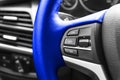 Cruise control buttons on the blue steering wheel of a modern car. Car interior details. Car detailing. Royalty Free Stock Photo