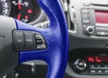 Cruise control buttons on the blue steering wheel of a modern car. Modern car interior details. Car detailing. Royalty Free Stock Photo