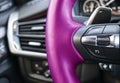 Cruise control buttons on the pink steering wheel of a modern car. Car interior details. Car detailing. Dashboard