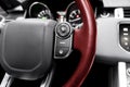 Cruise control buttons on the red perforated leather steering wheel of a modern car.  Car interior details Royalty Free Stock Photo