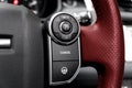 Cruise control buttons on the red perforated leather steering wheel of a modern car.  Car interior details Royalty Free Stock Photo