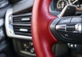 Cruise control buttons on the red steering wheel of a modern car, car interior details. Royalty Free Stock Photo