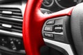 Cruise control buttons on the red steering wheel of a modern car, car interior details. Royalty Free Stock Photo