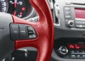 Cruise control buttons on the red steering wheel of a modern car, car interior details. Royalty Free Stock Photo