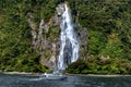 Cruise ferry and beautiful high waterfall in Milford Sound, Fiordland National park