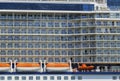 Cruise line ship side with lifeboats and balcony stateroom.