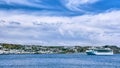 Cruise liner ship anchored in harbor of some Greek island. Traditional white houses, green hills, summer day, clouds Royalty Free Stock Photo