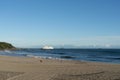 Cruise ship arriving at Mount Maunganui on horizon beyond breaking waves