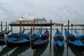 A cruise ship crossing the Venice lagoon early spring morning at dawn and blue gondolas anchored at the seafront. Royalty Free Stock Photo