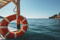 On a cruise ship, an orange lifebuoy is sheltered under an awning